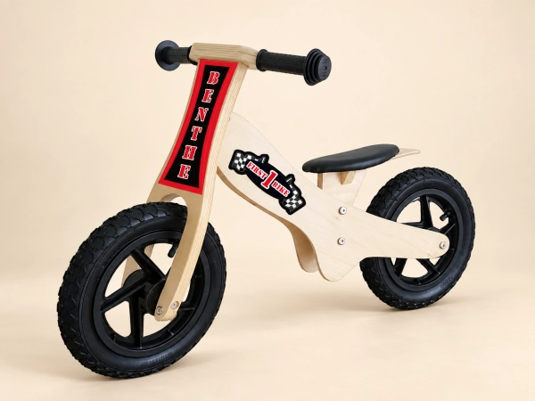Houten loopfiets met rode naamopdruk op een beige achtergrond