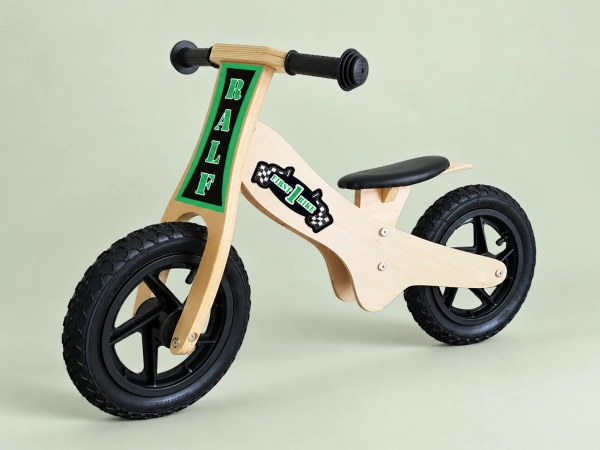 Houten loopfiets met groene naamopdruk op een lichtgroene achtergrond